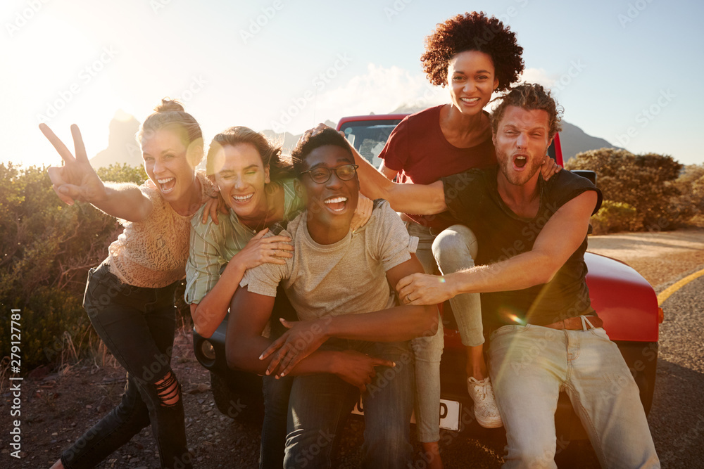 A diverse group of happy friends posing for a photo on a sunny day during a road trip adventure.
