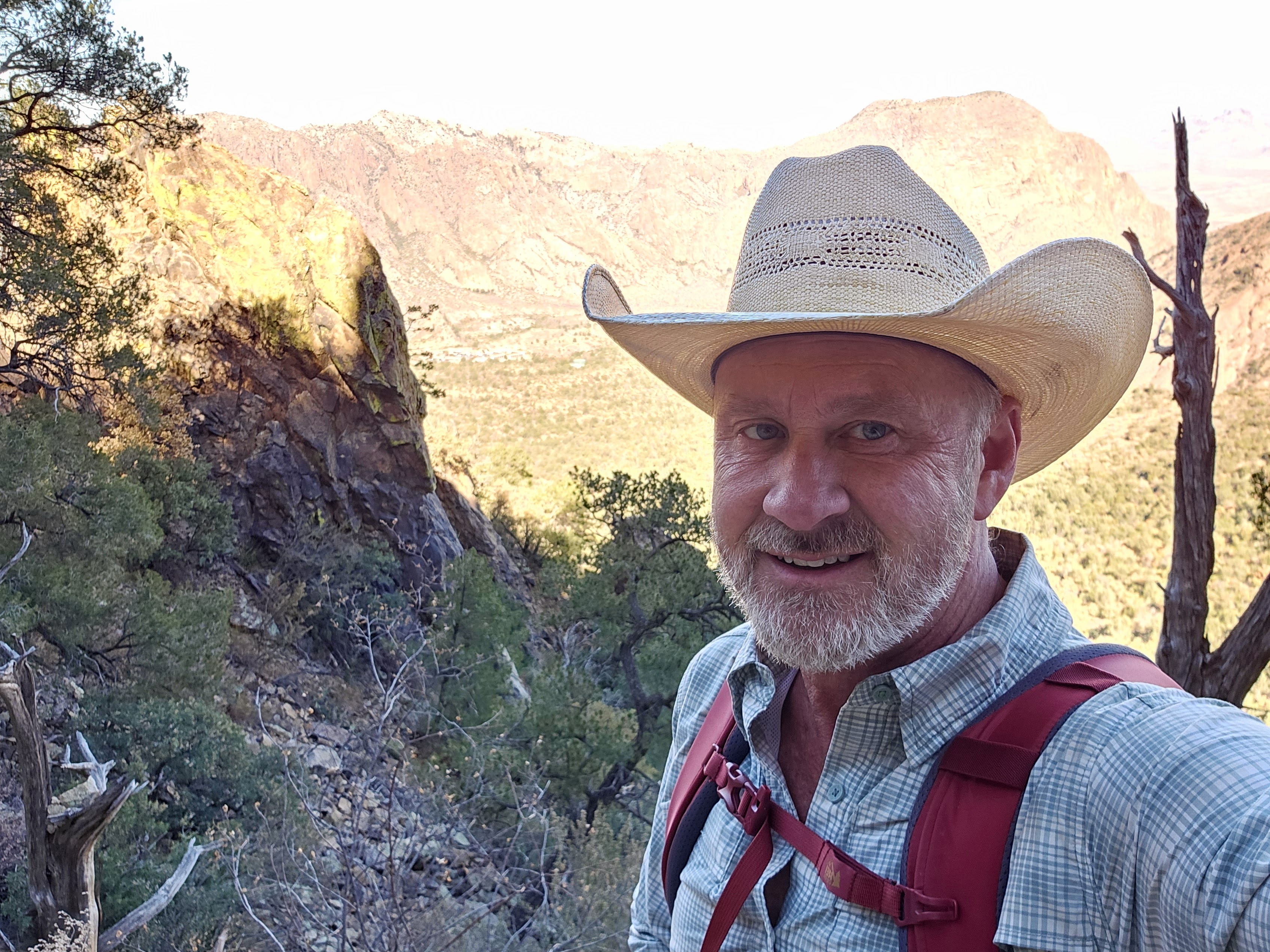 Terry hiking a mountain trail in a straw cowboy hat