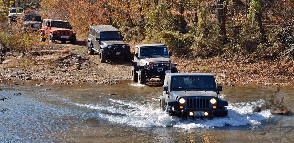 An off-road vehicle confidently crossing a creek, showcasing its capabilities.
