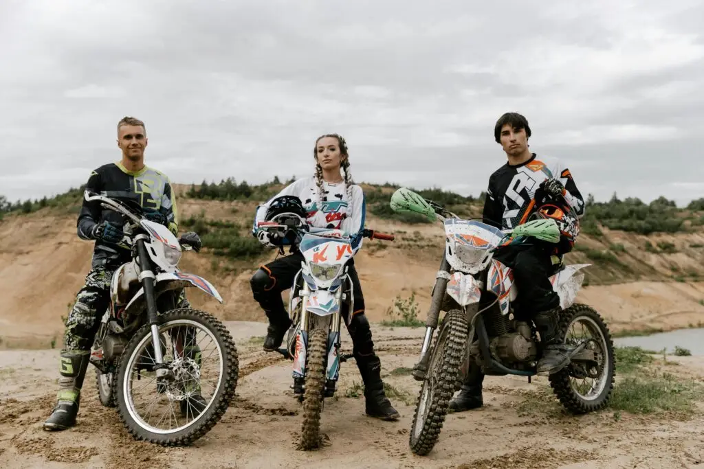 Three friends pose with their dirt bikes ready for an off-road motocross adventure.
